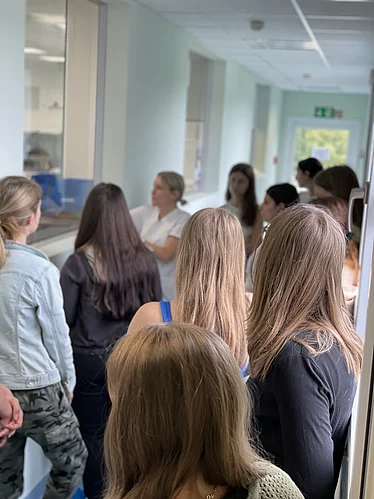 Leitende PTA Frau Bayerlein erklärt den PTA Schülerinnen und Schülern das aseptische Arbeiten mit Blick in die Reinräume des Aseptischen Zubereitungszentrums.